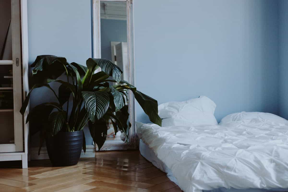 Full-length mirror leaning against a bedroom wall as a safer alternative to a mirror above the bed