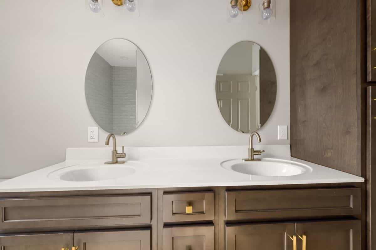 Double vanity with two oval mirrors illustrating single versus double vanity mirror choices Modern bathroom with twin mirrors and stylish faucets, illustrating single versus double vanity mirrors