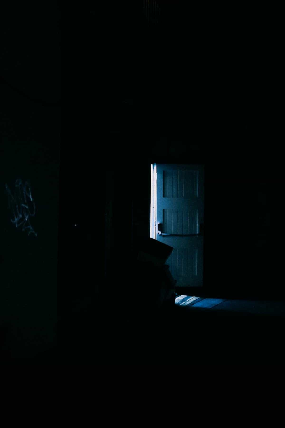 Dark moody doorway suggesting threshold veil and portal symbolism in spiritual language Dimly lit mysterious interior doorway casting long shadows suggesting threshold and spiritual portal symbolism