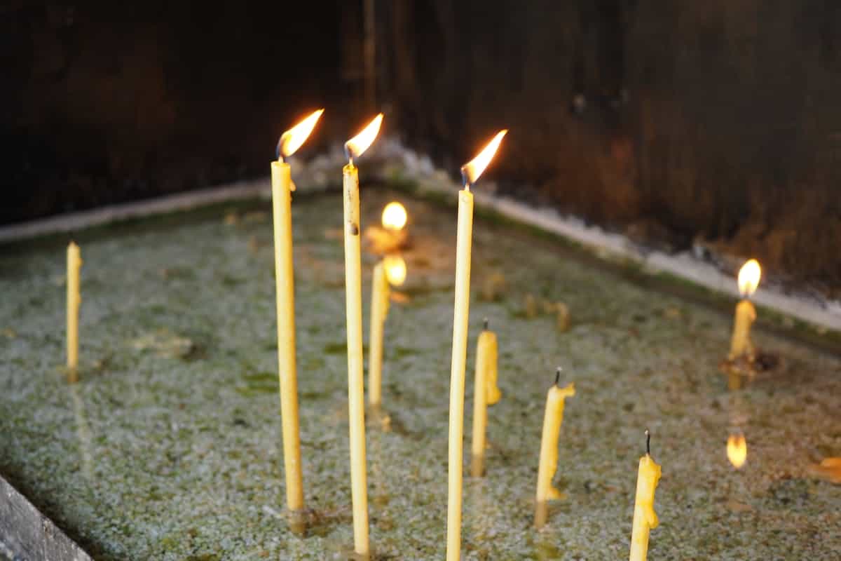 Close-up of softly burning wax candles in warm low light suggesting contemplation