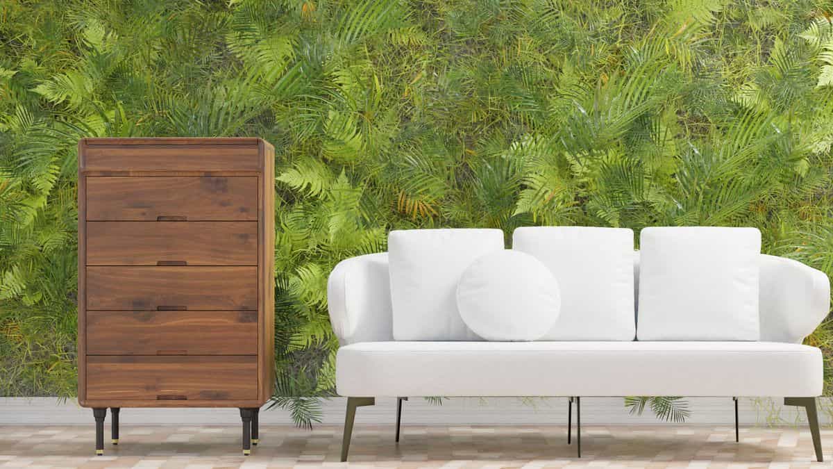 Living room with a green plant wall illustrating a greenery accent wall idea Modern living room with a lush green plant wall and a white sofa, illustrating a greenery accent wall