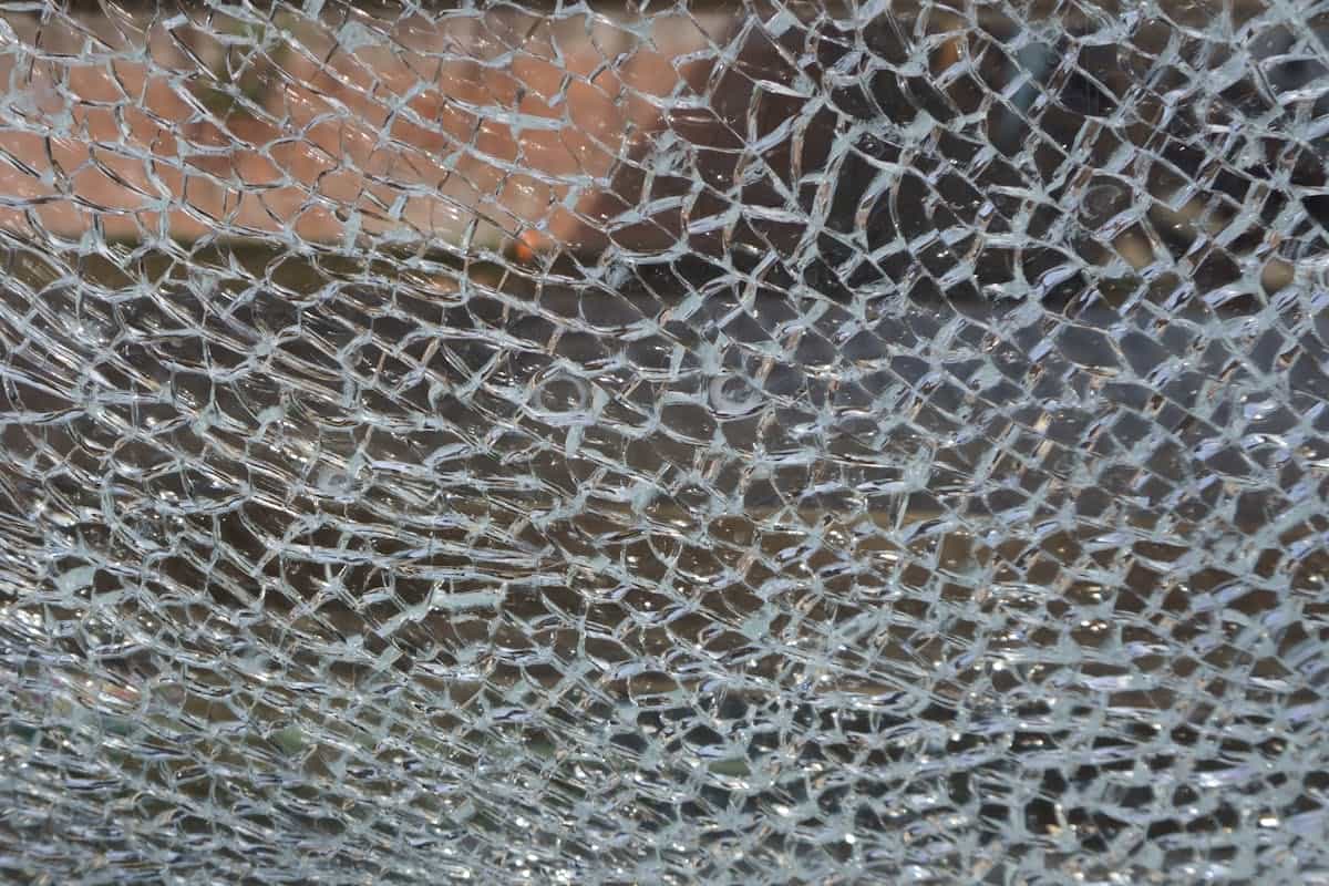 Detailed view of shattered glass pieces creating a textured silver pattern symbolizing breakage and release