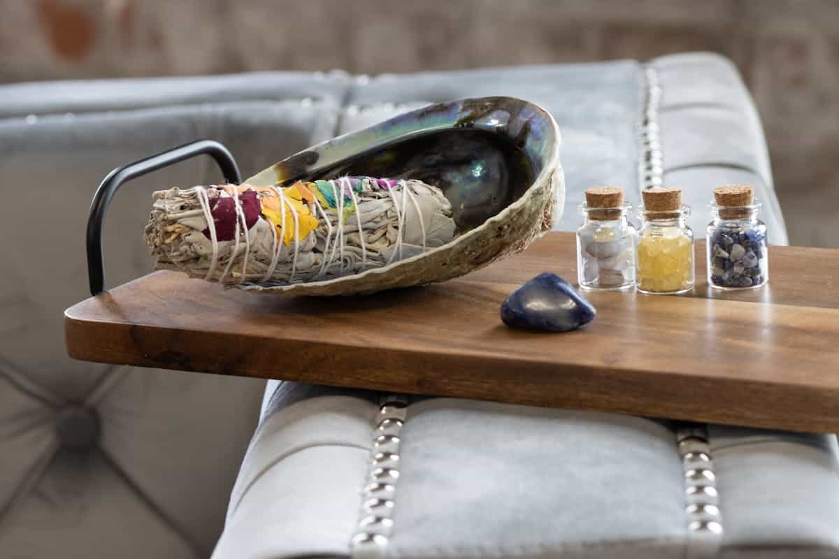 A serene setup with sage, crystals, and healing bottles representing the spiritual cleansing rituals commonly recommended after a mirror falls from the wall