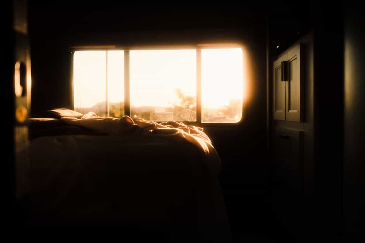Sunlit bedroom illustrating finding your personal feng shui sleeping direction by Kua number Tranquil bedroom bathed in warm sunrise light through the window, illustrating personalised feng shui sleeping direction