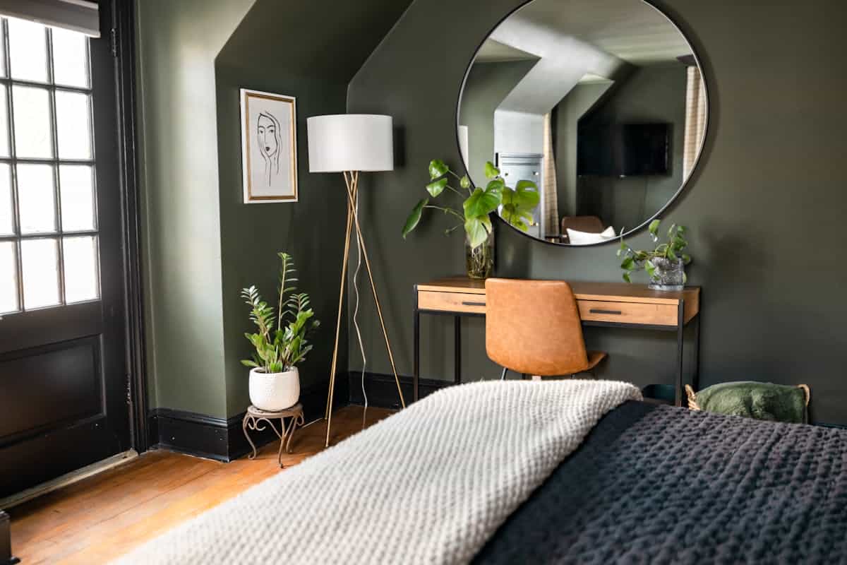 Calm green-toned bedroom with natural light showing feng shui considerations for a mirror over the bed