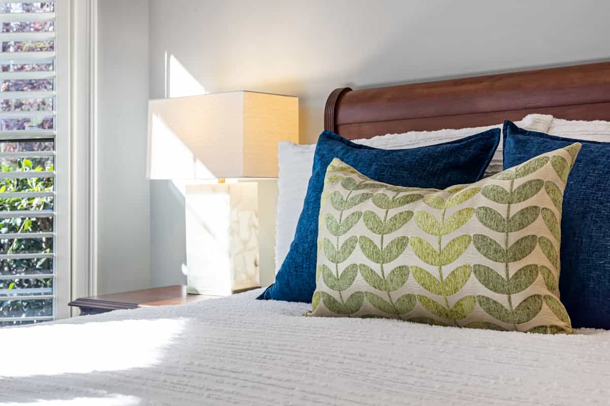 Bedroom with colorful pillows illustrating how to add feng shui bedroom colors through accents Inviting bedroom with decorative pillows and warm sunlight, illustrating how to add feng shui color through accents