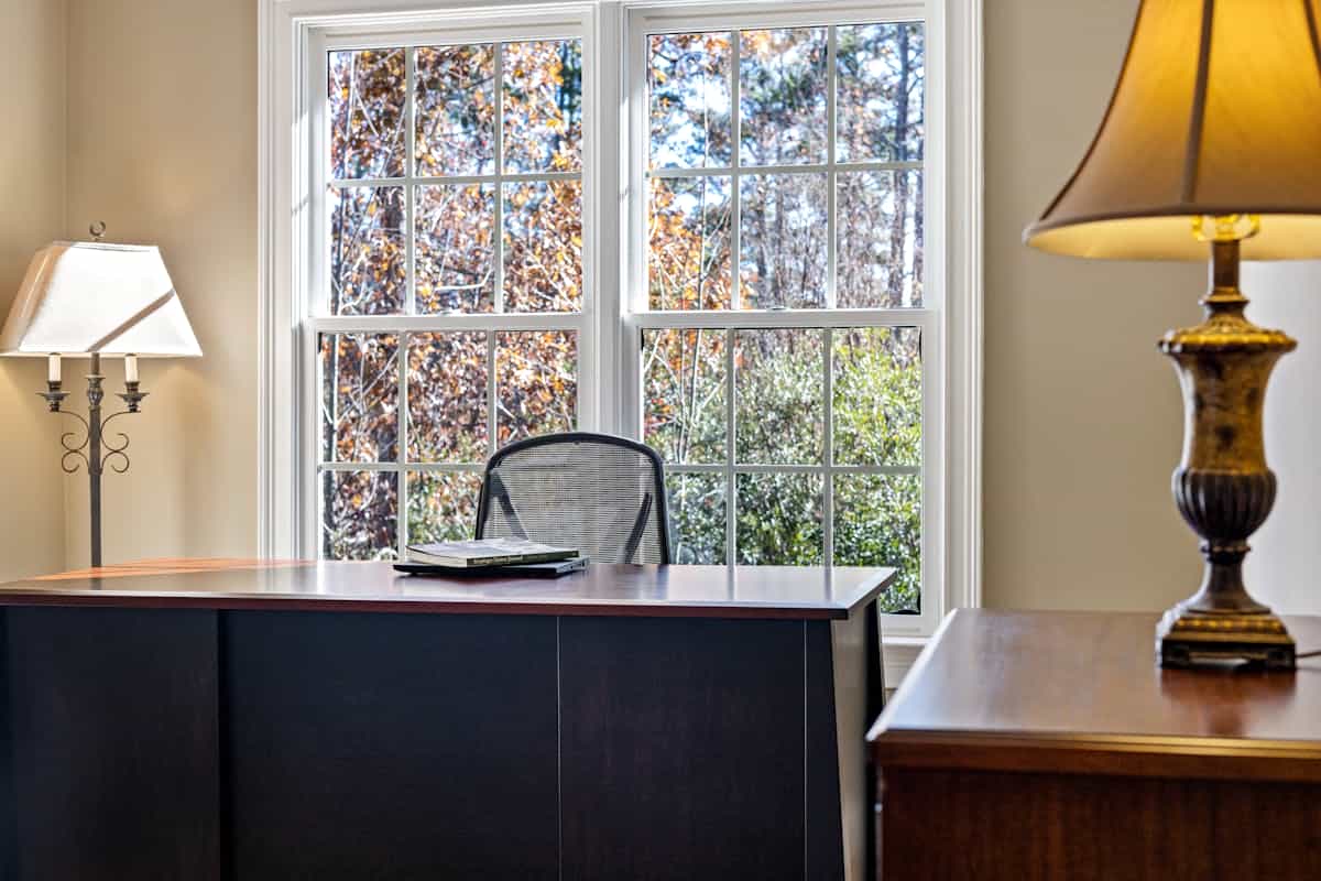 Cozy home office with a desk and lamp beside a sunlit window, illustrating feng shui office lighting