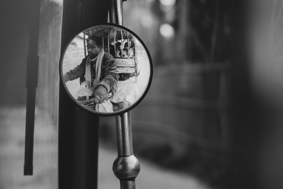 Black and white reflection of a person seen in a small mirror rearview style composition