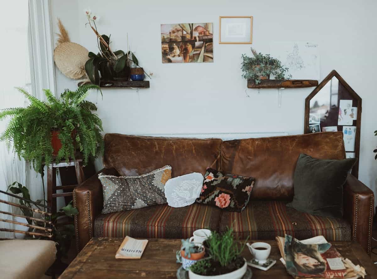 Living room in warm earth tones illustrating grounding feng shui living room colors Cozy living room with a leather sofa, plants and warm rustic tones, illustrating grounding feng shui earth colors