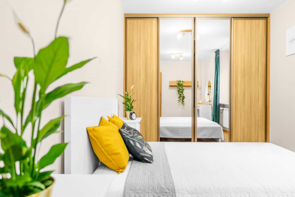 Bedroom with a mirrored closet beside the bed illustrating where a wardrobe mirror should face