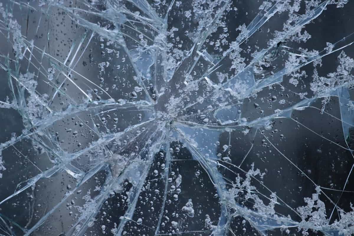 Close-up of frosted shattered glass with water droplets suggesting fragile sharp edges needing careful handling
