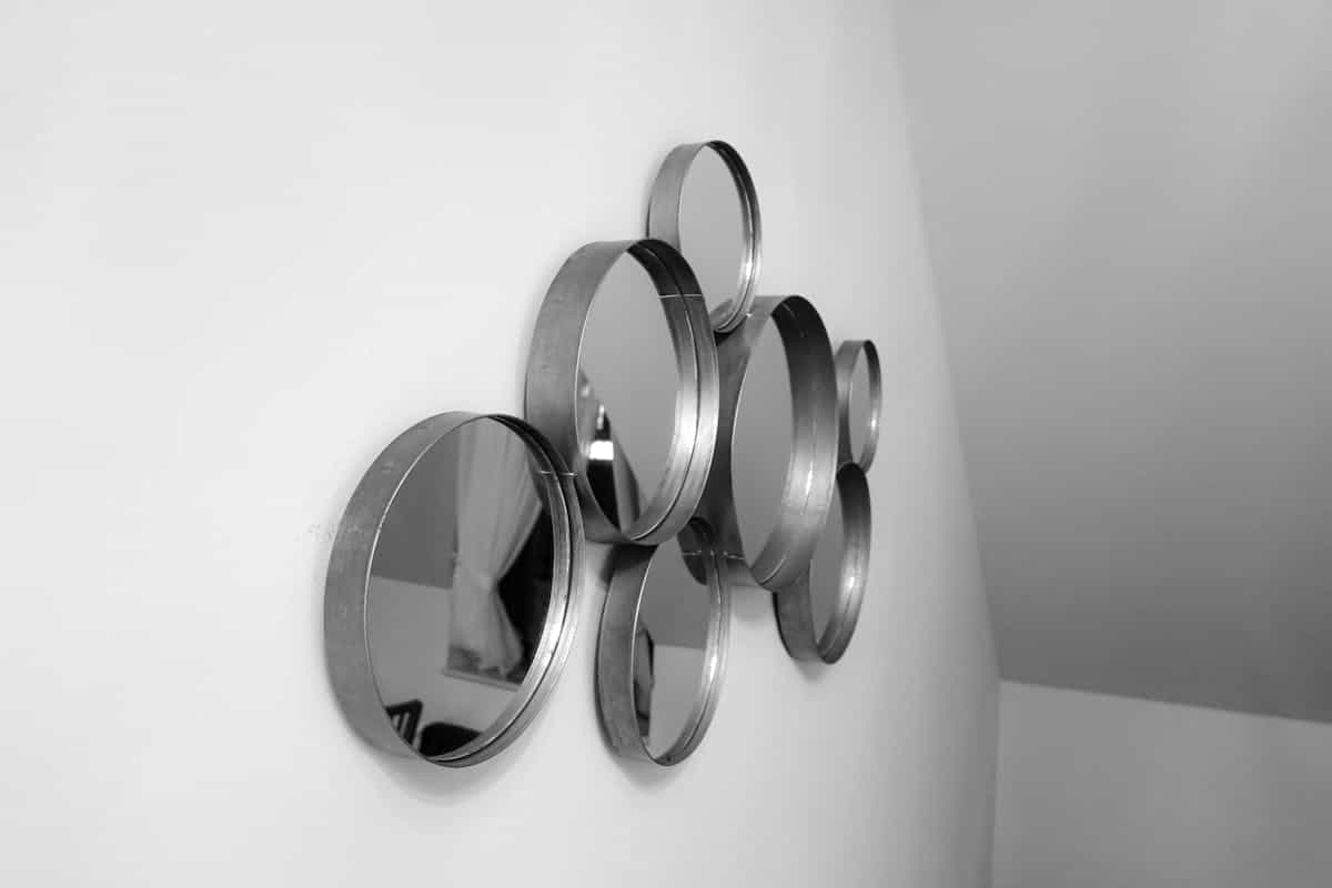 Cluster of circular mirrors mounted as decorative wall art in a bright interior