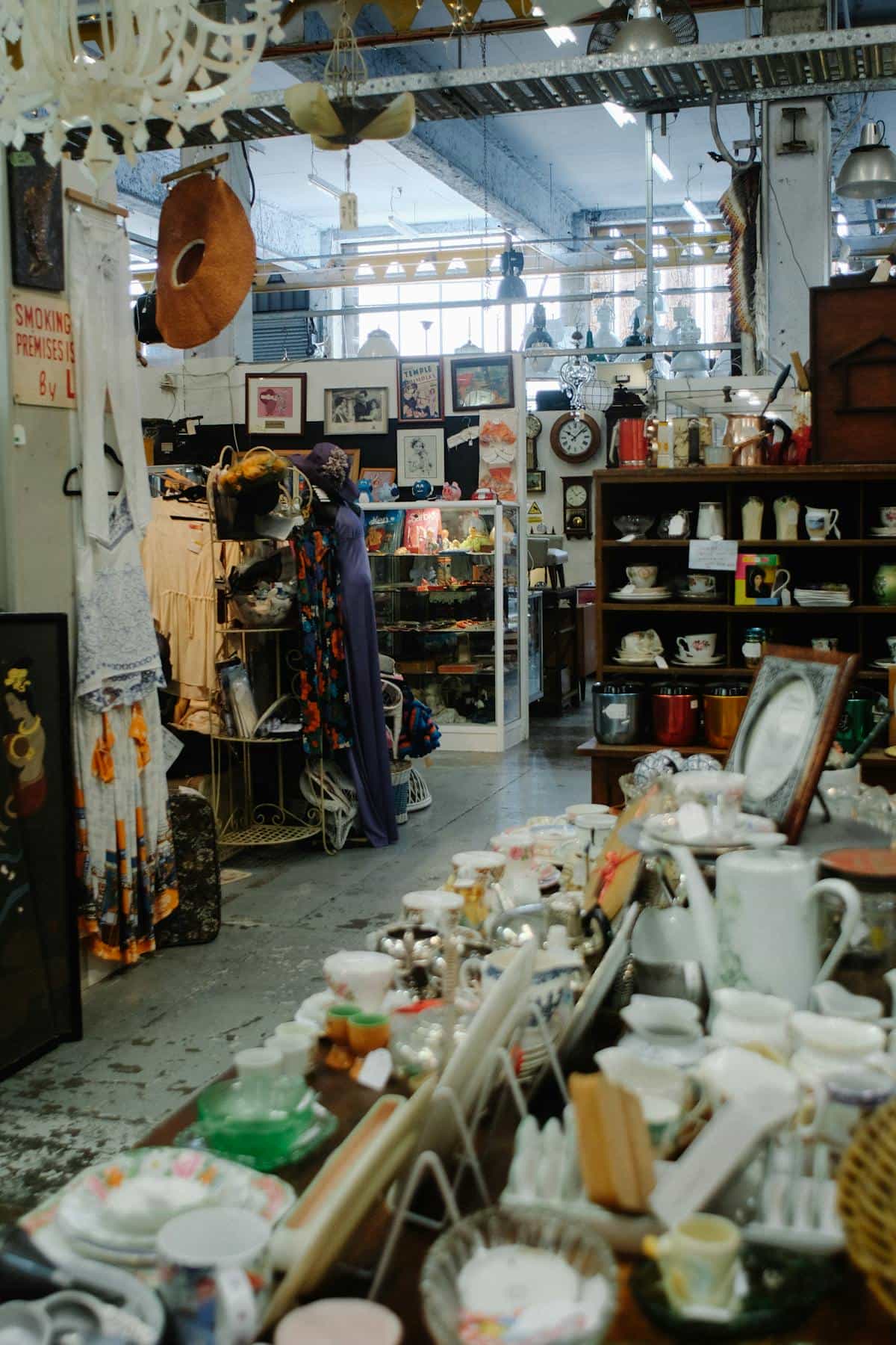 Aisle of secondhand thrift store with clothing racks and warm overhead lighting