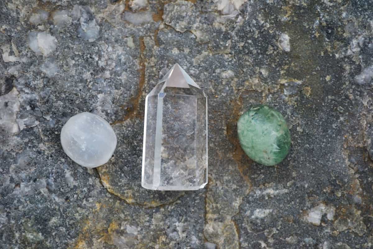 Assortment of selenite and clear quartz crystal healing stones arranged on a light surface in natural sunlight