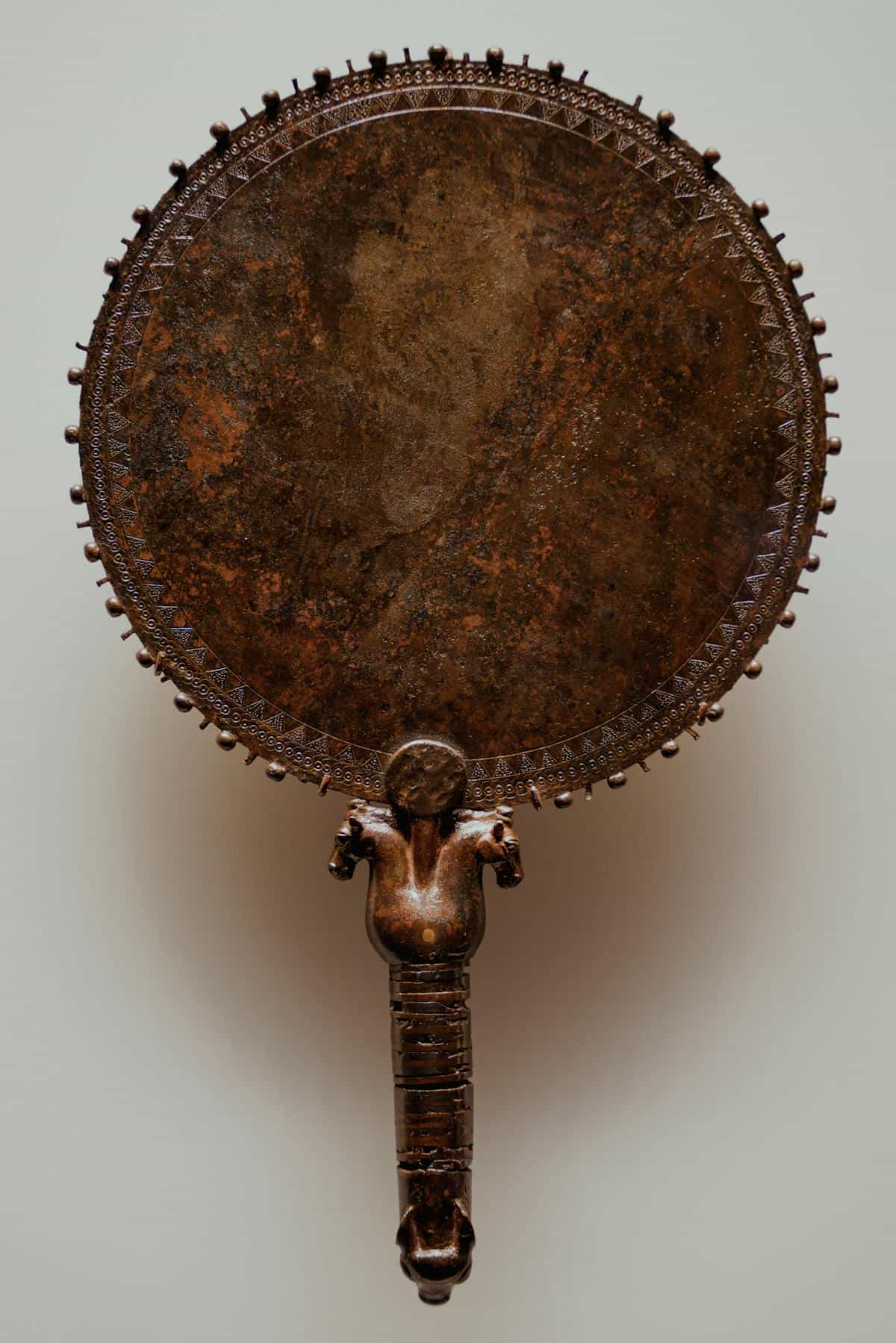 Ornate bronze hand mirror representing ancient mirrors and soul symbolism history Decorative bronze hand mirror with ornate handle evoking ancient mirror craft and historical spiritual beliefs
