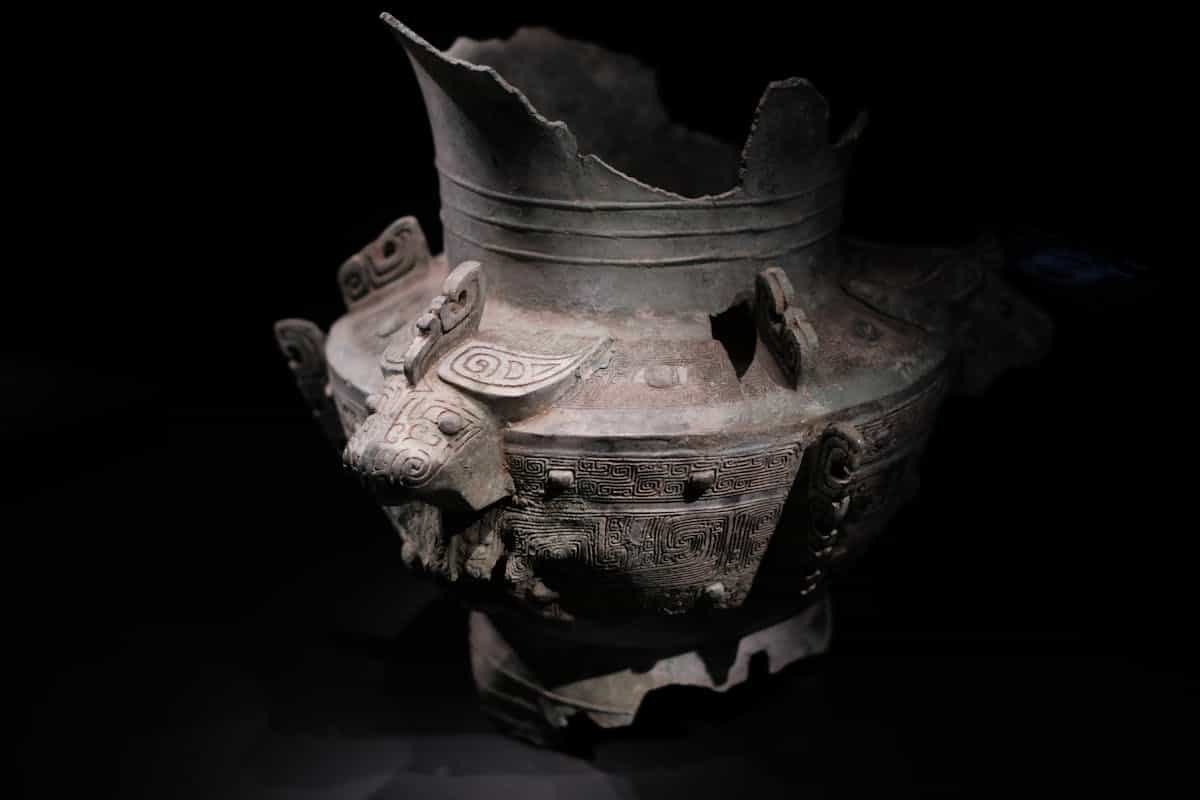 Beautifully detailed ancient Chinese bronze vessel with decorative patterns on display representing the ancient world of bronze mirrors and the history of reflection in sacred contexts