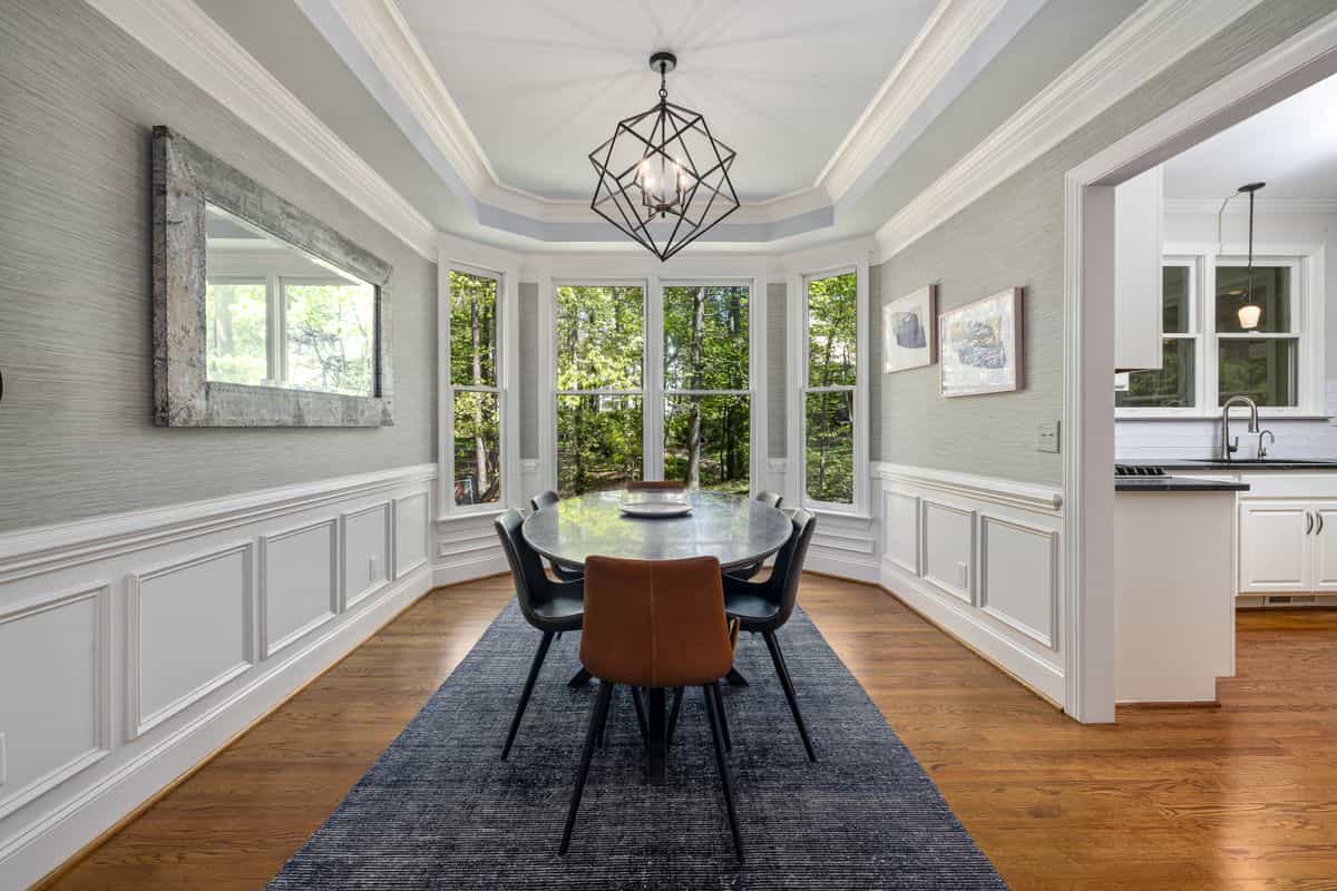 Dining room with large windows and a wall mirror reflecting daylight, showing why mirrors for a dining room brighten the space