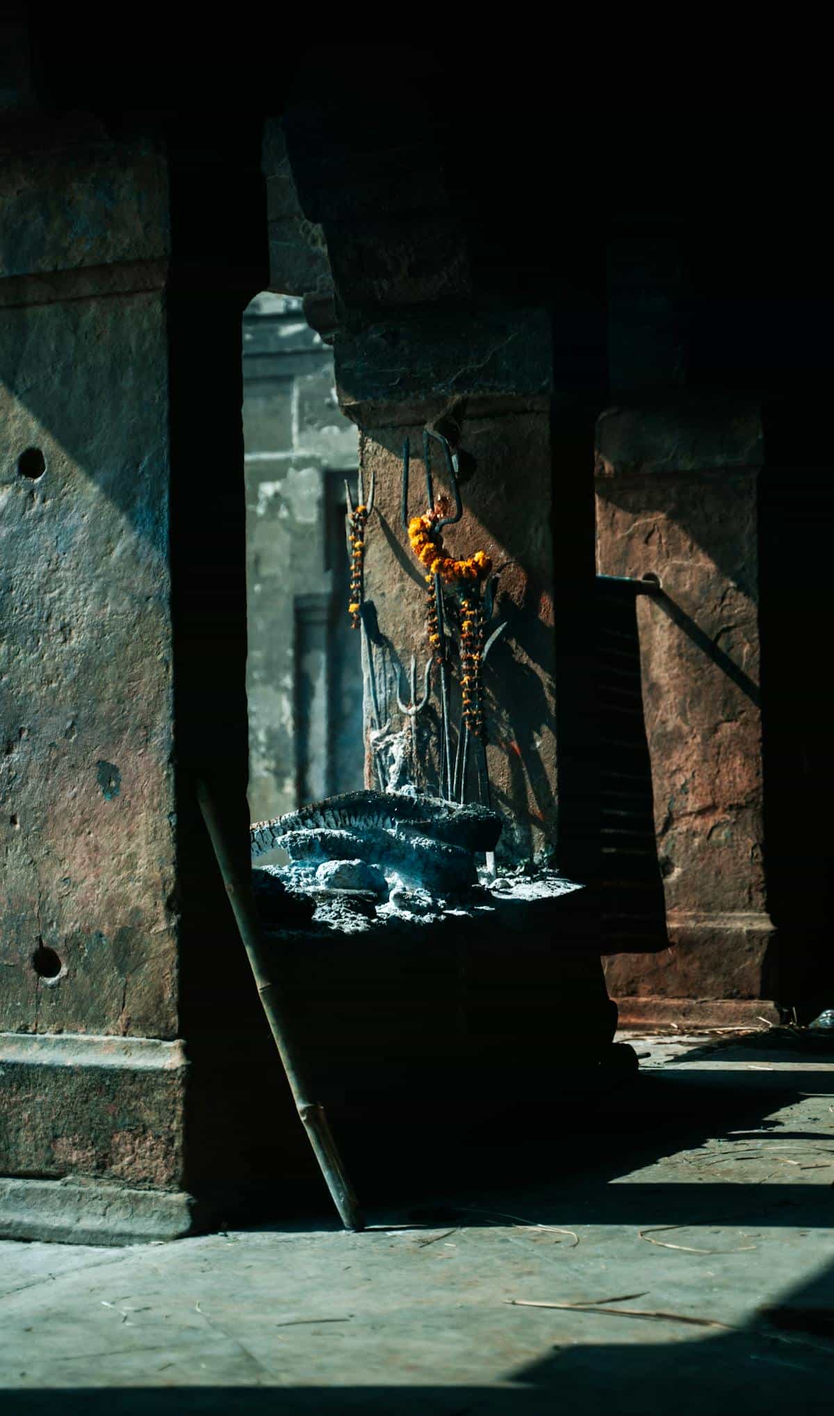 Atmospheric view inside an ancient temple with ash remnants and marigold garlands in Varanasi evoking the sacred space where Darpana rituals are performed