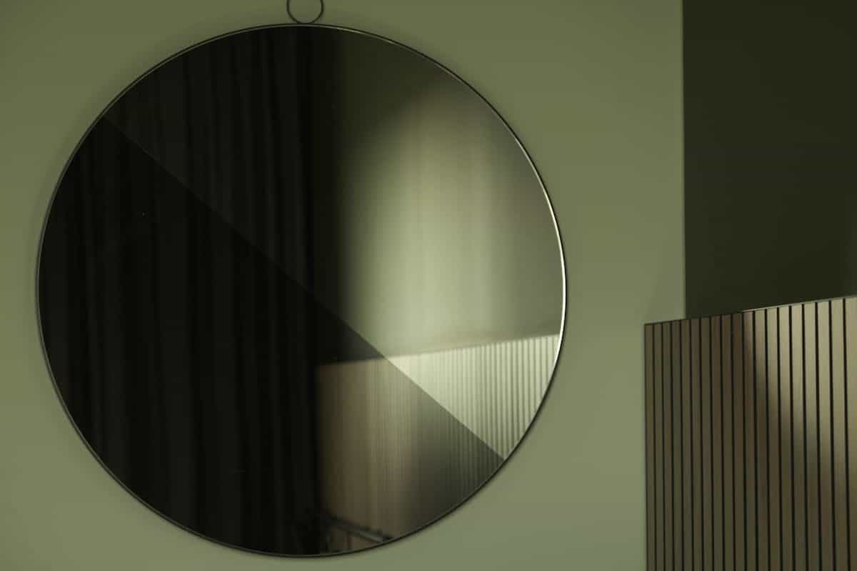 A large circular mirror reflecting soft light in a modern interior.