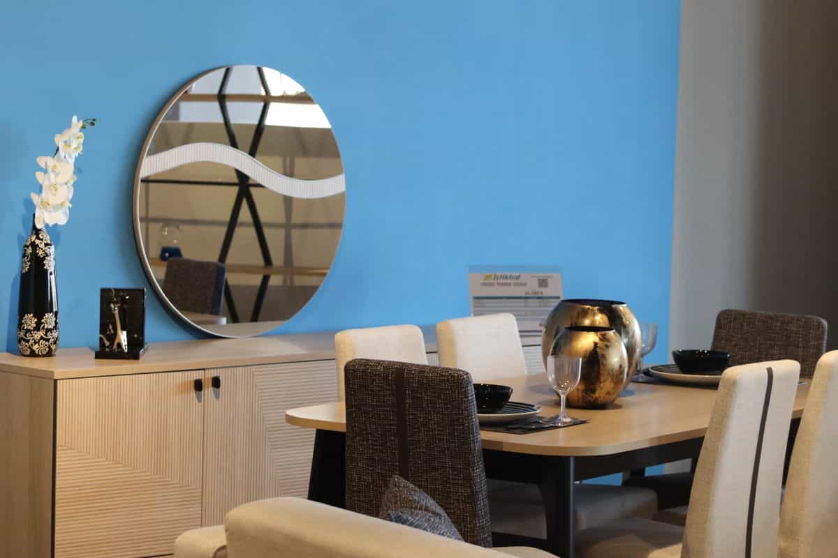 Sleek dining room with a round mirror on the wall showing the best mirror shape for a dining room