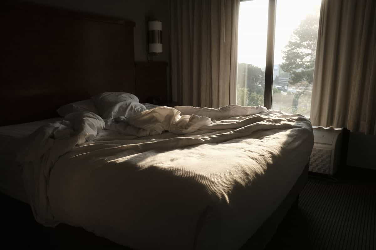 Bed in morning light illustrating balancing feng shui sleeping direction with the commanding position Comfortable bed in soft morning light, illustrating balancing feng shui sleeping direction with bed placement