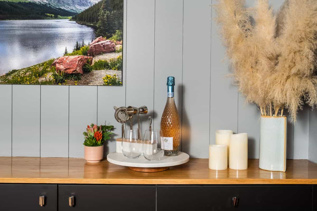 Styled sideboard with art and candles showing how high to hang a large mirror over a dining buffet