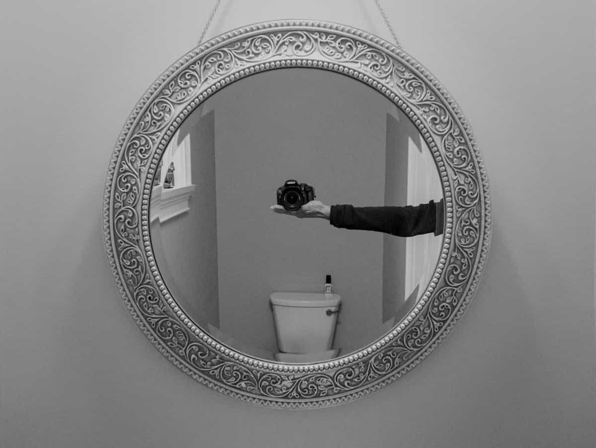 Black round mirror in a modern monochrome setting illustrating black round mirror decor Round mirror in a monochrome modern bathroom setting, illustrating a black round mirror