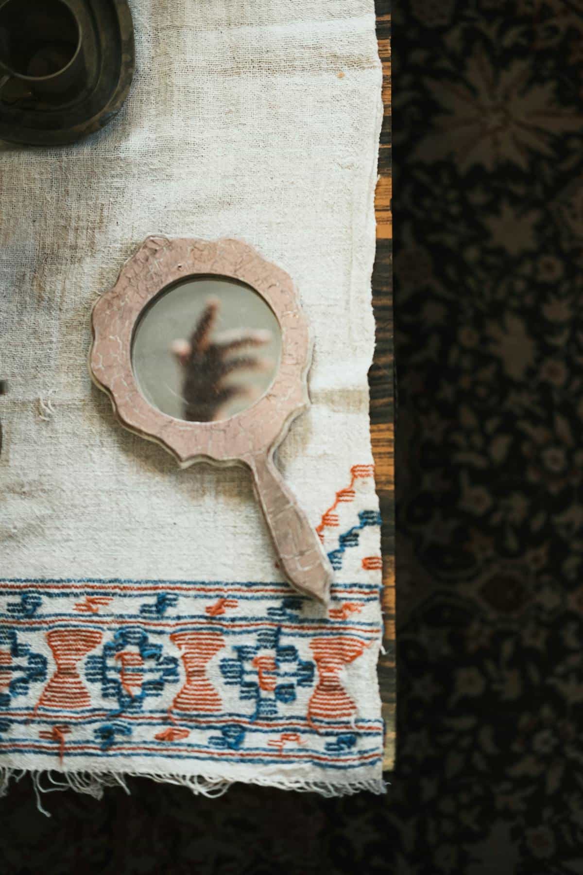 Vintage style handheld vanity mirror with metal frame on textured surface