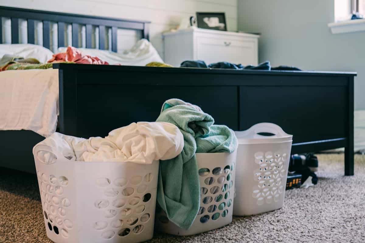 Cluttered bedroom illustrating bad feng shui caused by disorder around the bed Cluttered bedroom with laundry baskets full of clothing on the floor, illustrating bad feng shui from clutter