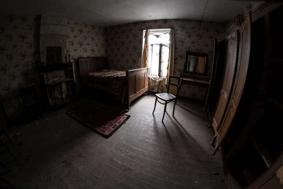 Dark atmospheric bedroom with vintage furniture and moody atmospheric lighting suggesting a mysterious night setting
