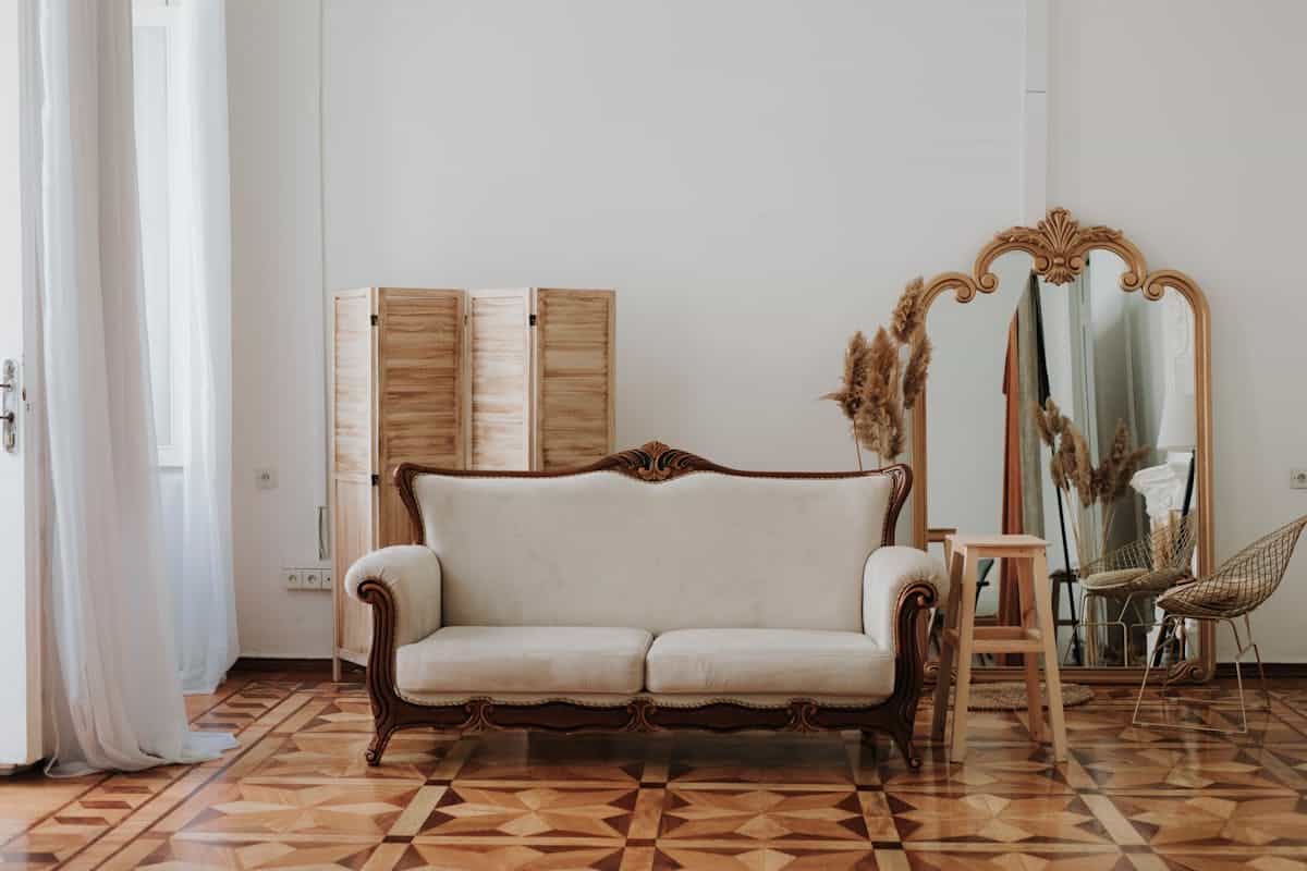 Living room with a floor mirror illustrating a mirror behind a sofa as an alternative to hanging Spacious living room with a vintage sofa and an elegant floor mirror, illustrating a mirror behind a sofa