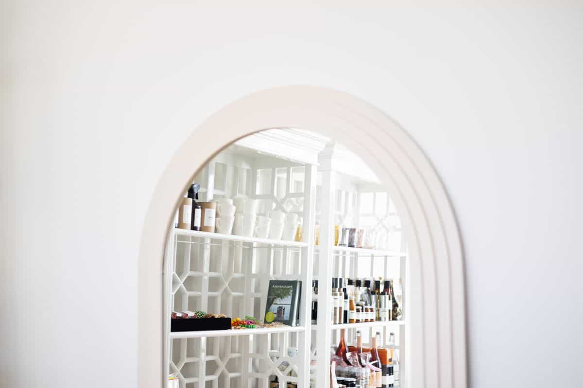 Arched doorway in a minimalist interior illustrating why an arched mirror reads as architecture Minimalist interior with an arched doorway and modern white shelves, illustrating why an arched mirror wall works