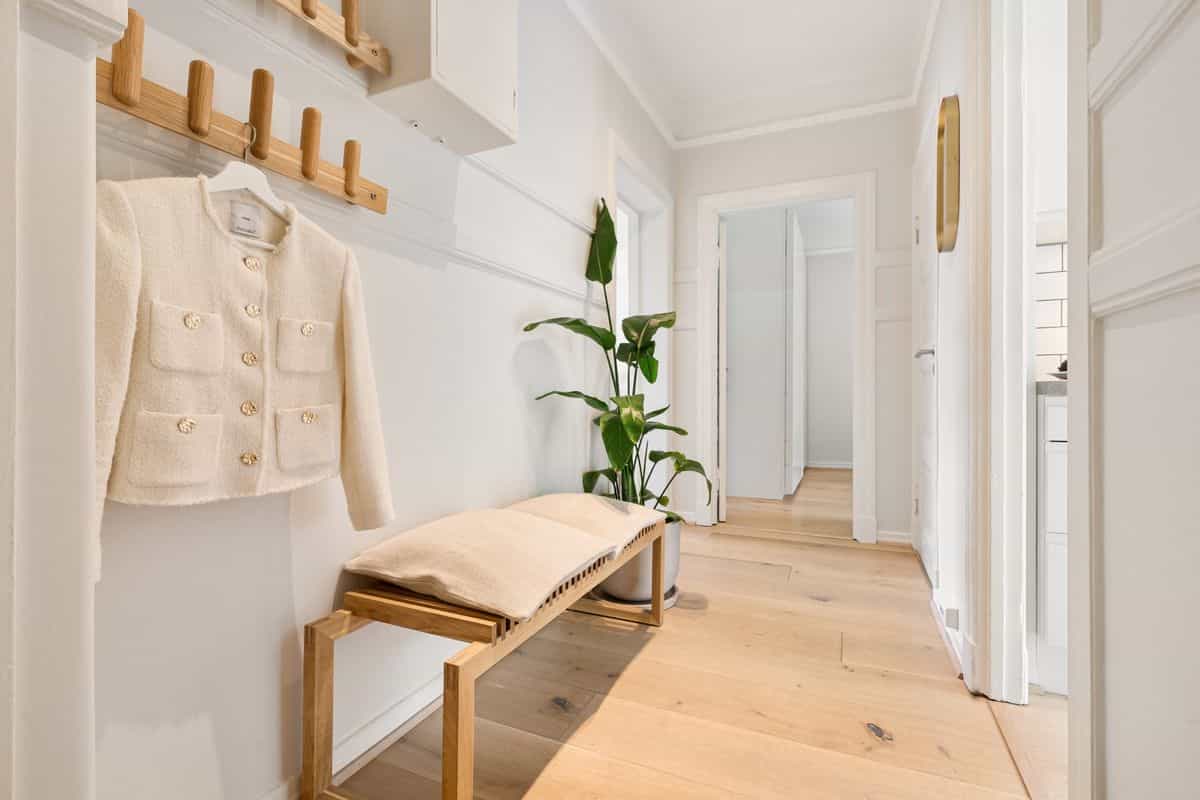 Minimalist wooden entryway illustrating styles of entryway mirror with hooks Bright minimalist hallway with wooden furniture and a coat area, showing entryway mirror with hooks styles