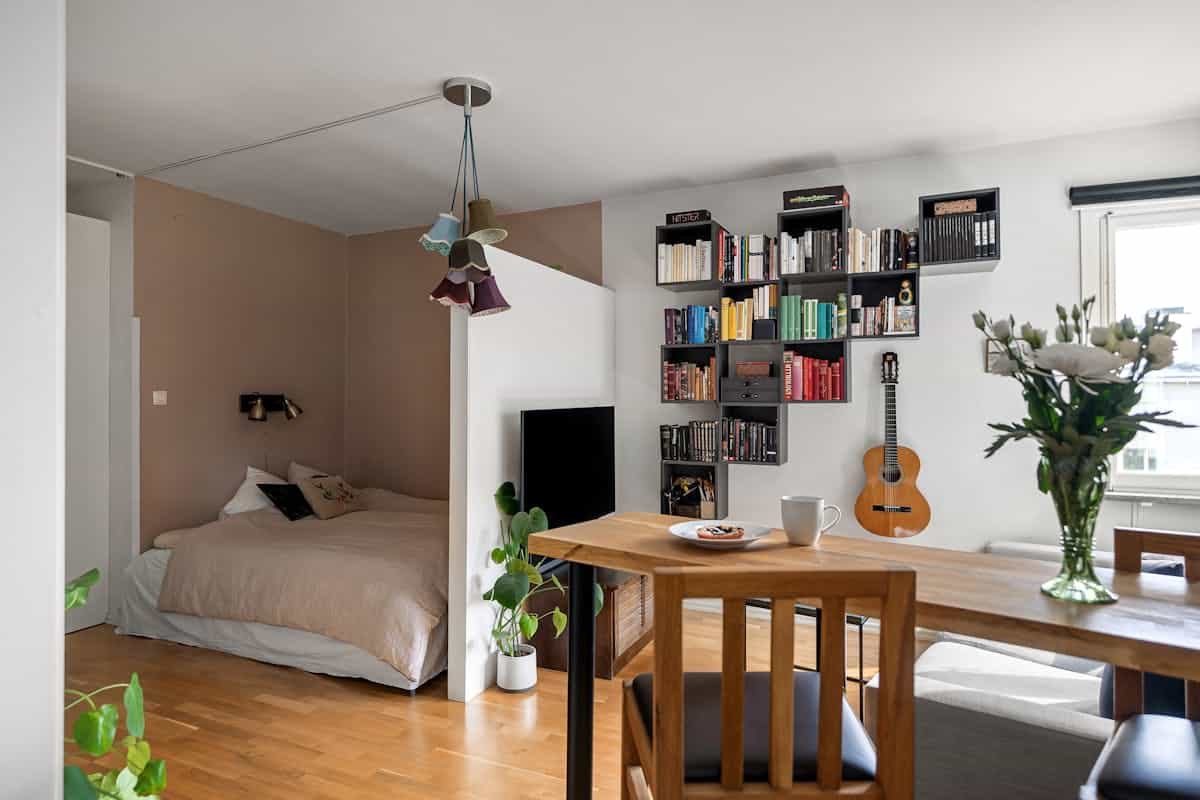 Studio bed in a defined corner illustrating the commanding position in a small space Studio apartment with a cozy bed and bookshelf in a defined sleeping corner, illustrating feng shui bed placement