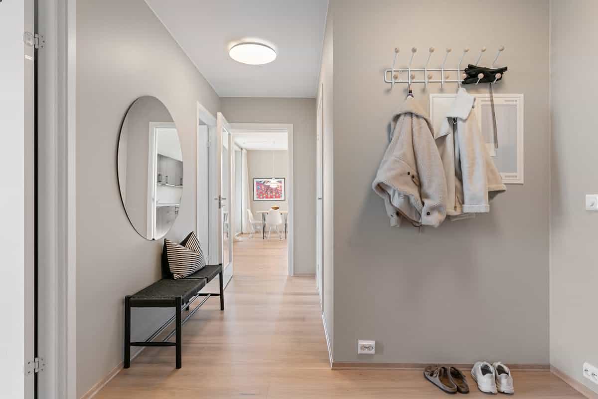 Entryway with coats and shoes illustrating why an entryway mirror with hooks is useful Contemporary hallway with coats and shoes by the door, showing the storage an entryway mirror with hooks replaces