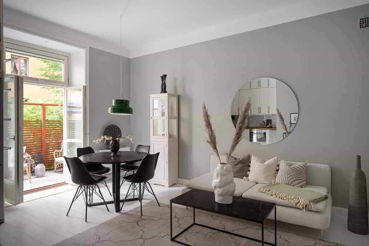 Dining room with a round mirror above a black dining table as a dining room mirror idea