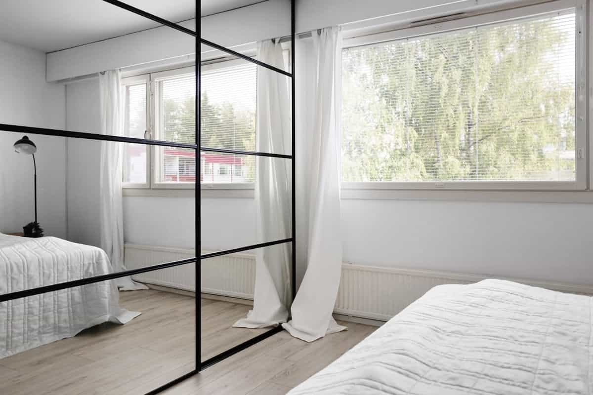 Modern minimalist bedroom with large wall mirrors demonstrating secure mirror mounting above the bed