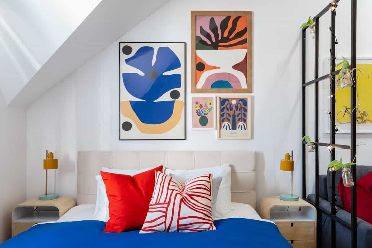 Bedroom gallery wall illustrating a framed-art arrangement for bedroom wall decor Bedroom with a colorful arrangement of framed art on the wall, illustrating a bedroom gallery wall