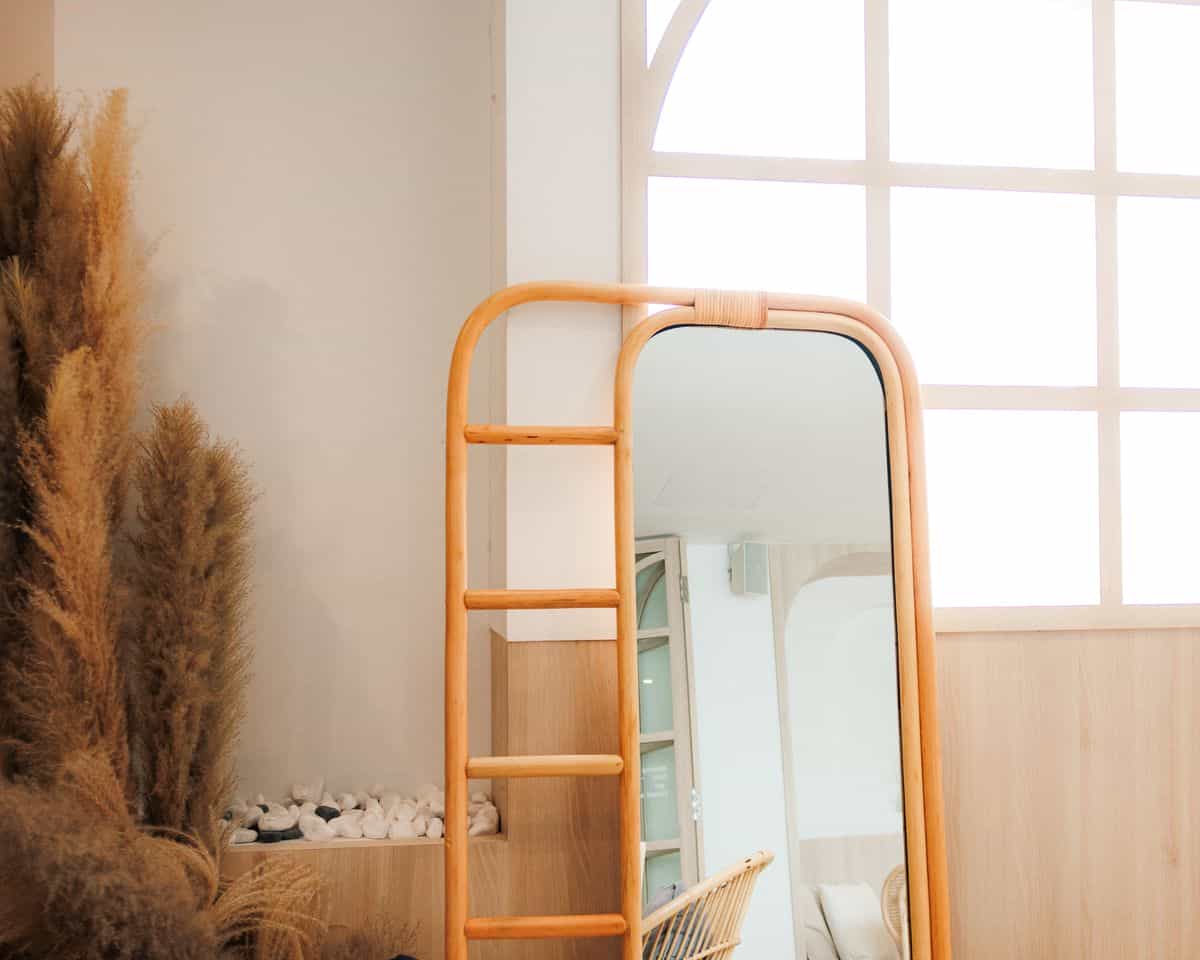 Minimalist interior with a natural wood framed full length mirror and sunlight, illustrating wooden full length mirrors