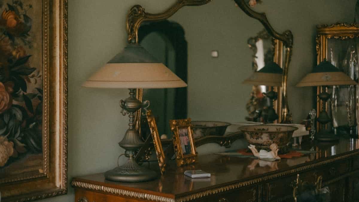 Vintage interior design featuring ornate mirrors, an antique lamp, and a wooden cabinet, representing the serious spiritual practices that still surround mirror use in modern traditions
