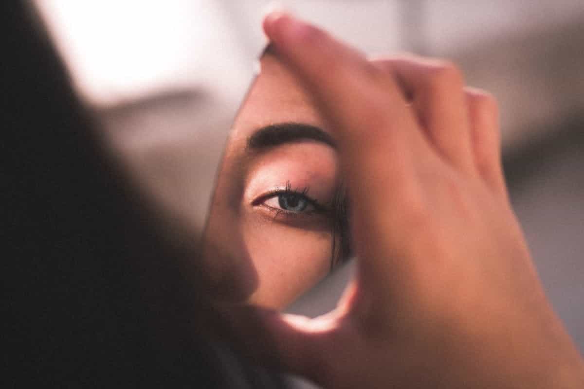 Eye reflected in broken mirror shard illustrating duality of truth and distortion Woman's eye reflected in broken mirror shard with soft lighting symbolising fractured perception and illusion in mirror symbolism