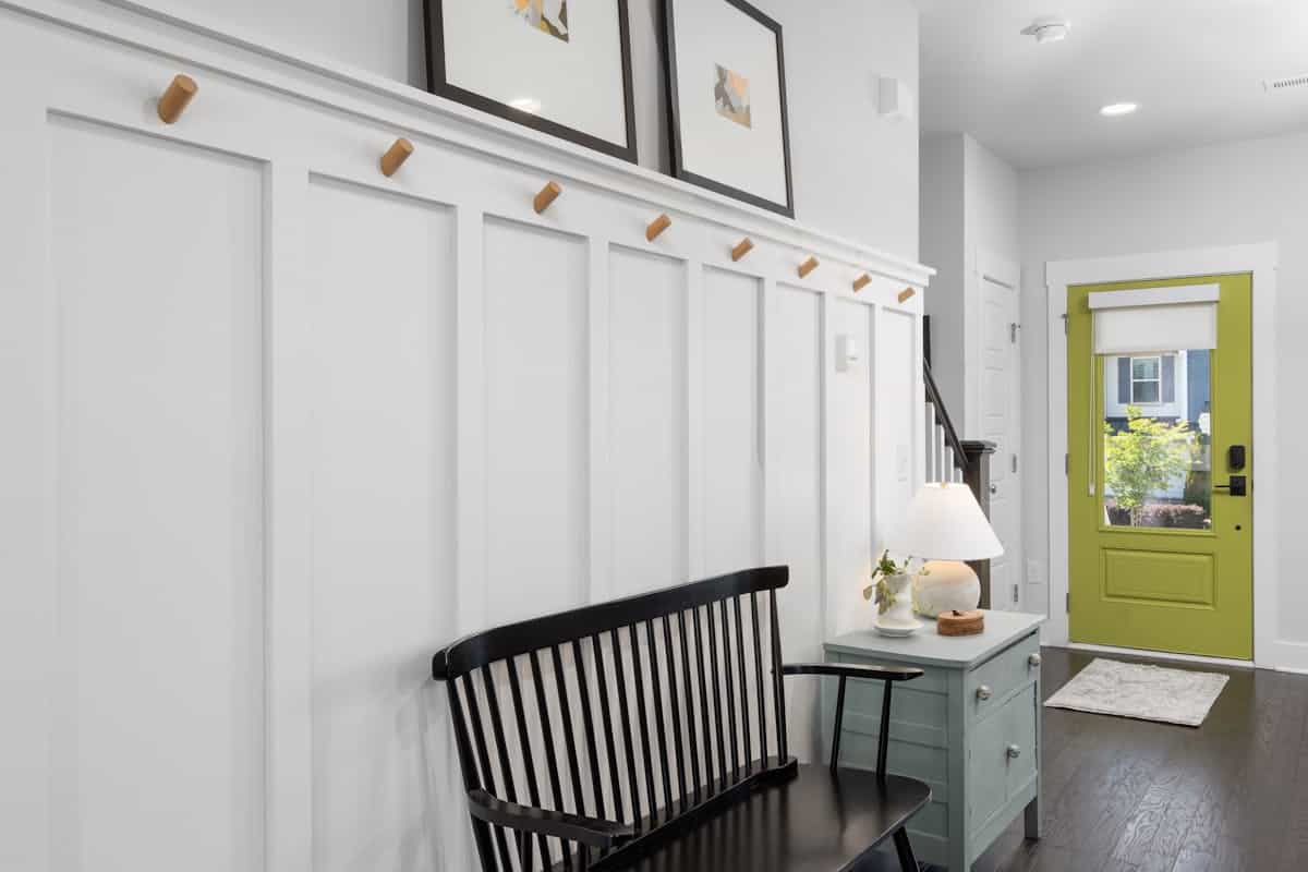 Stylish entryway illustrating how to style an entryway mirror with hooks as a drop zone Stylish entryway with a green door, bench, and decor, showing how to style an entryway mirror with hooks