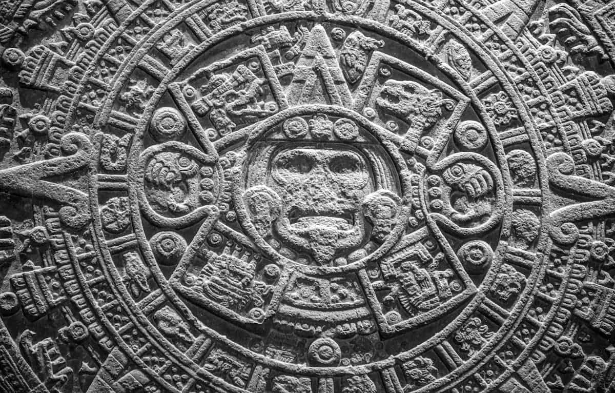Close-up of the Aztec calendar stone showcasing ancient craftsmanship in Mexico City, representing the deep Mesoamerican tradition of black obsidian mirrors used in ritual communication with Tezcatlipoca