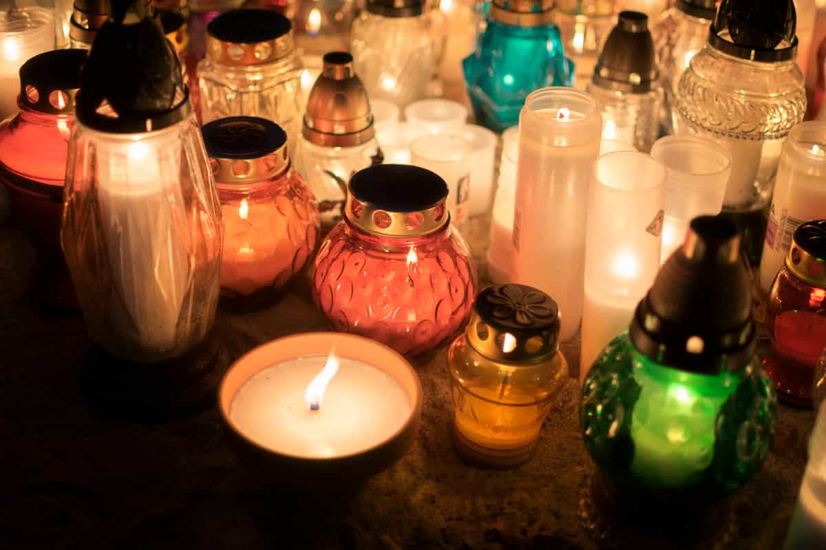 Colorful votive candles creating a warm spiritual ambiance at an outdoor memorial representing the connection between covering mirrors in mourning and the biblical call to redirect attention from vanity to eternity during grief