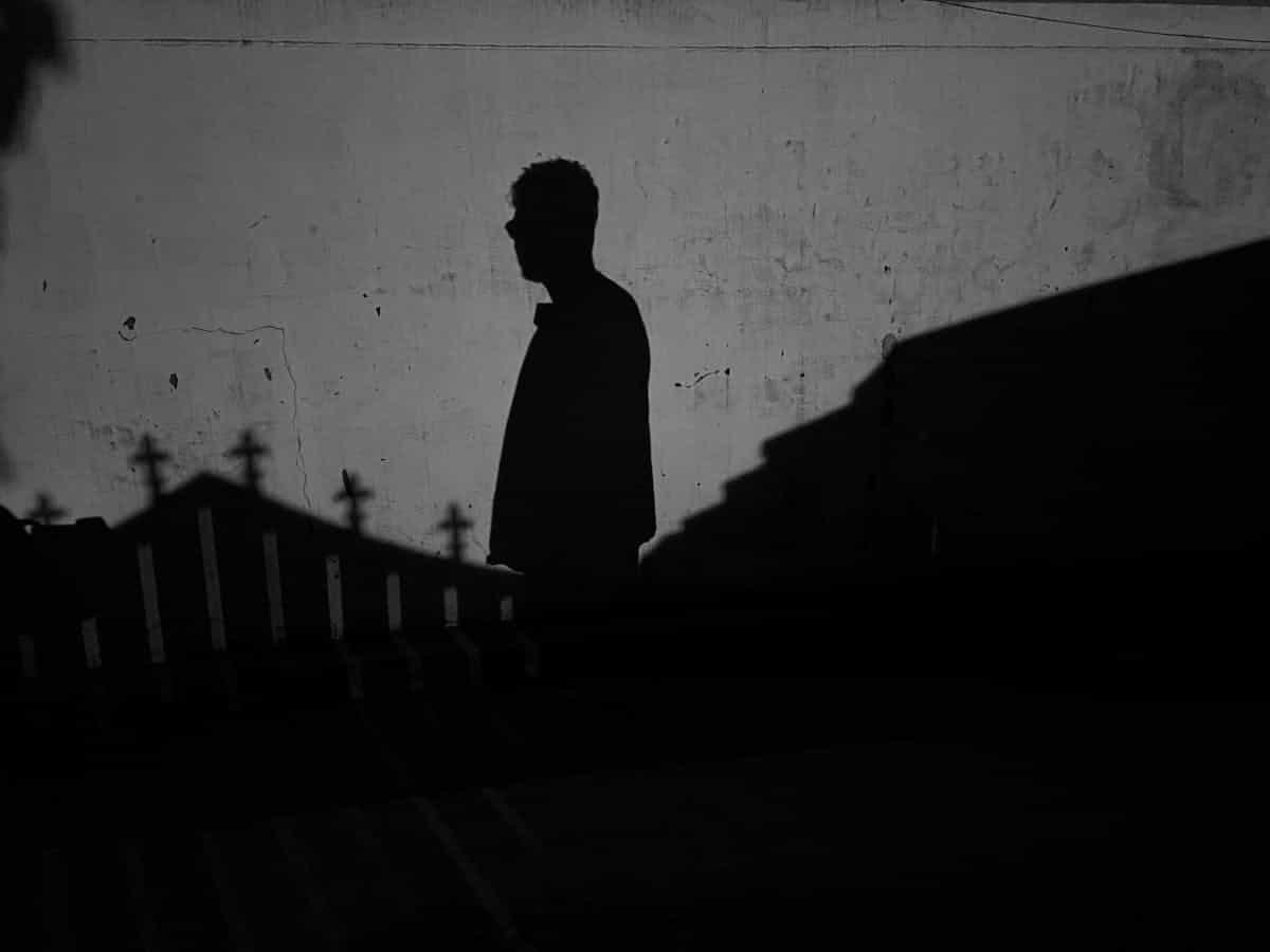 Dark dramatic silhouette of a man against a twilight wall representing the Jungian shadow self that appears as a stranger in mirror dreams