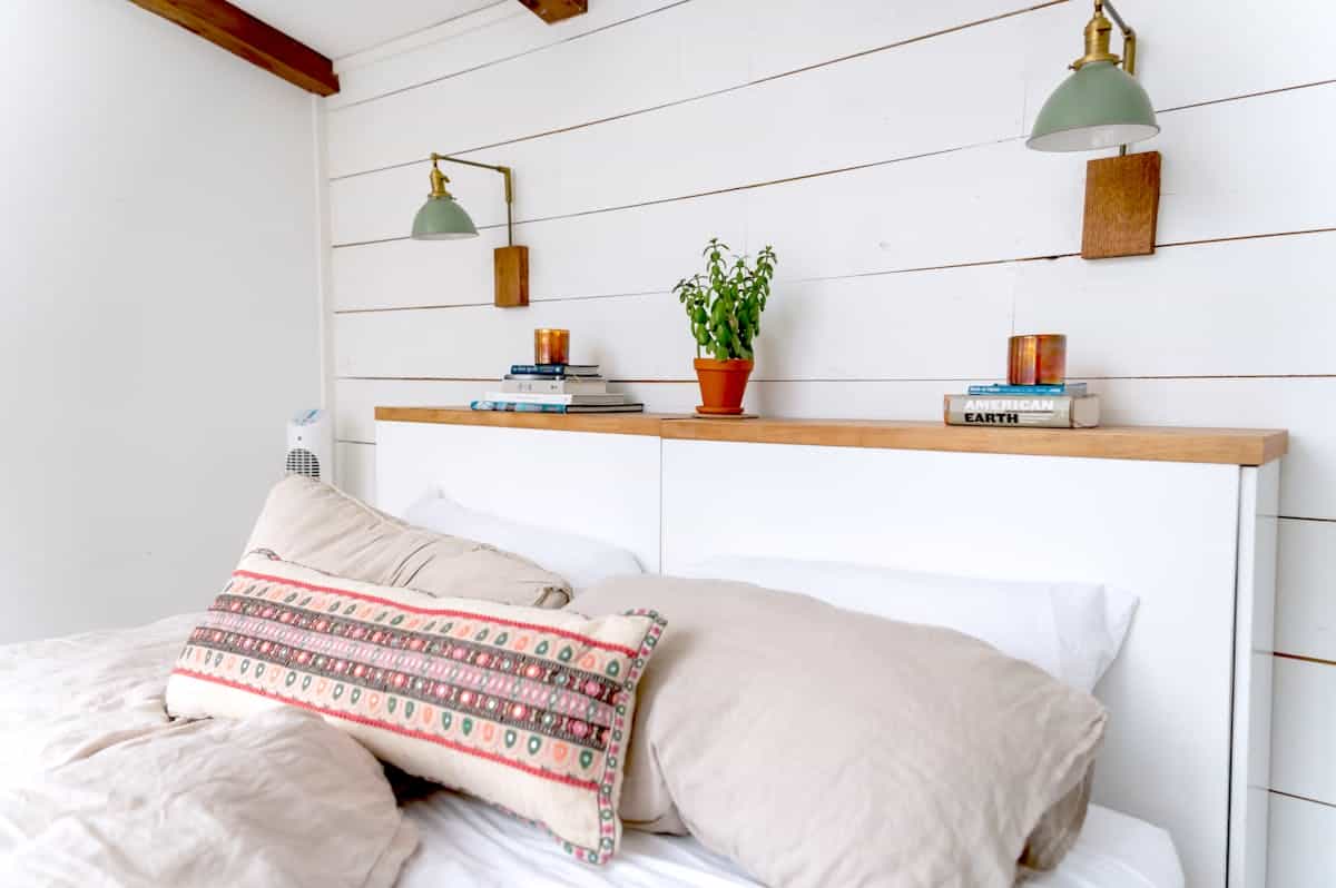 Bedroom with plants and soft wall lighting illustrating lighting as bedroom wall decor Minimalist bedroom with hanging plants and soft lighting, illustrating wall lighting and greenery in bedroom decor