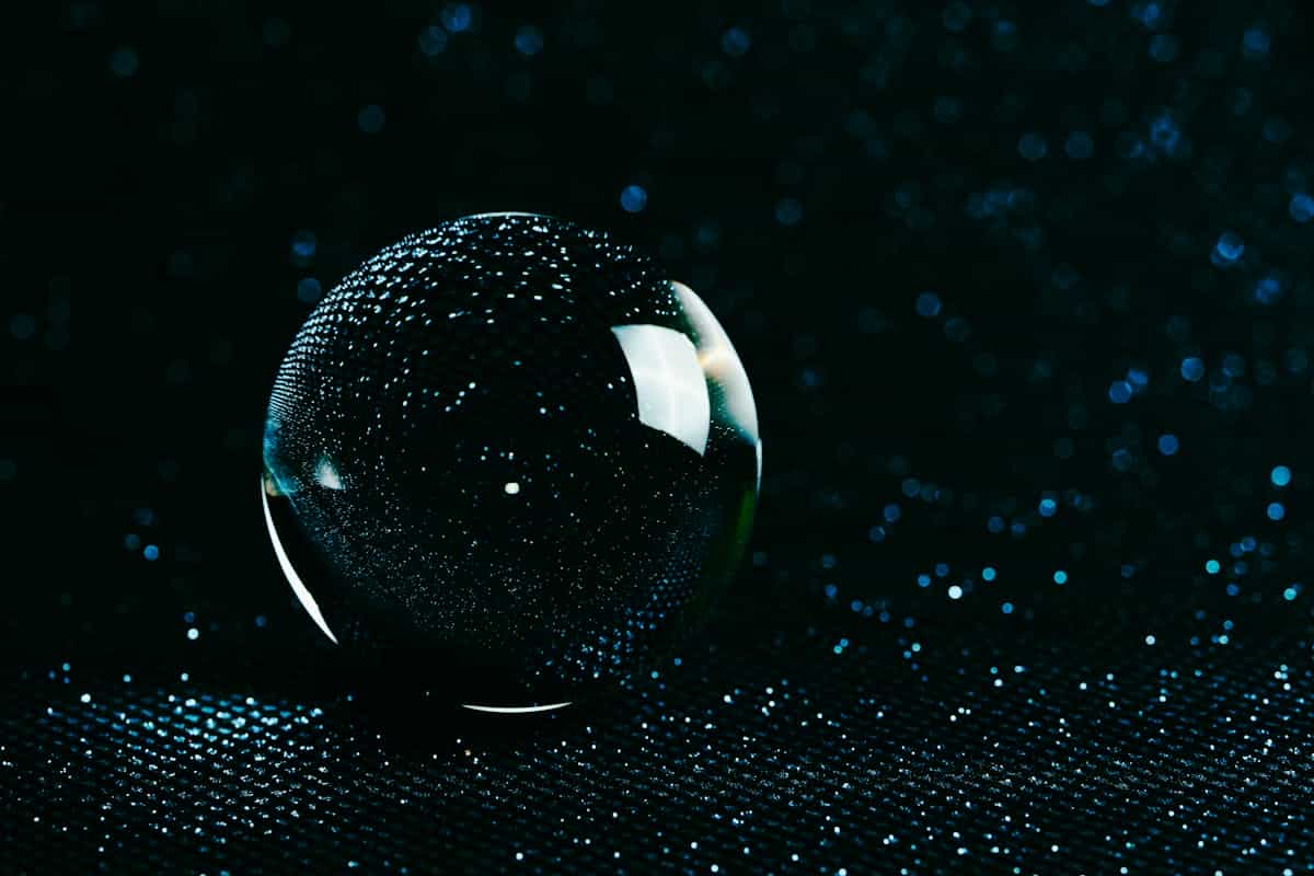 Glowing glass sphere with water droplets on a deep black studio background