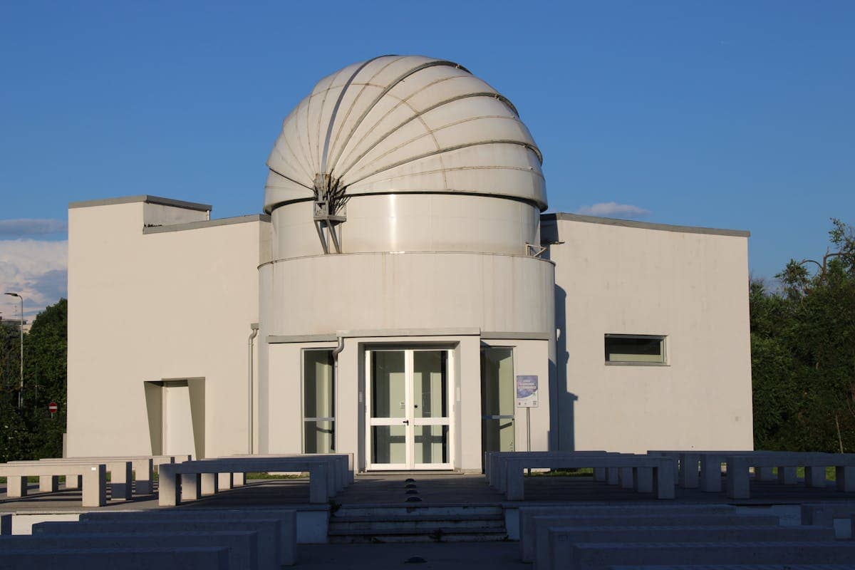 White domed astronomical observatory surrounded by greenery showing how mirror precision spans from everyday household use to the scientific frontier of gravitational wave detection and space telescope optics