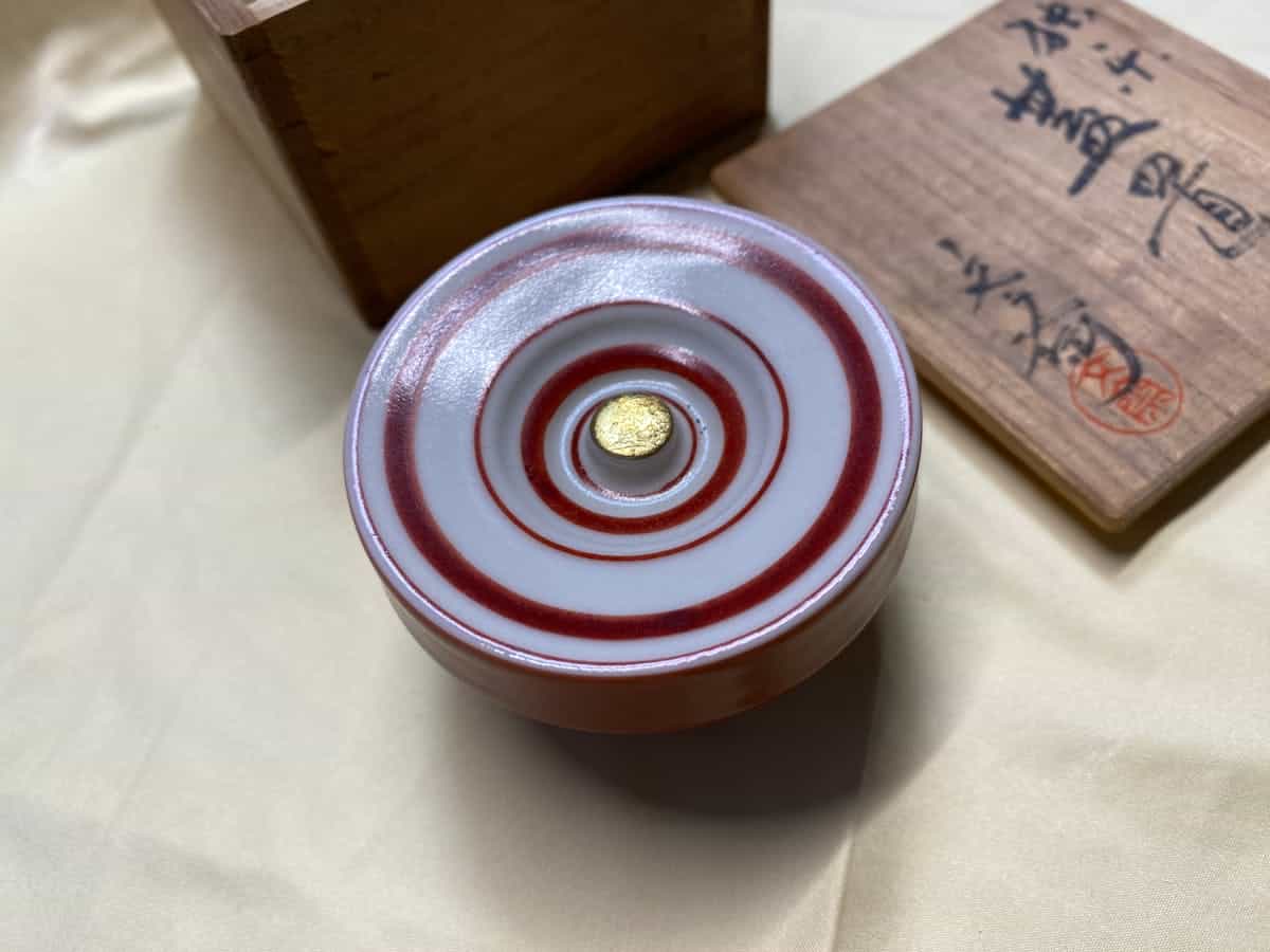 A handcrafted Japanese ceramic bowl with a red spiral design representing the Kintsugi philosophy of beauty in repair