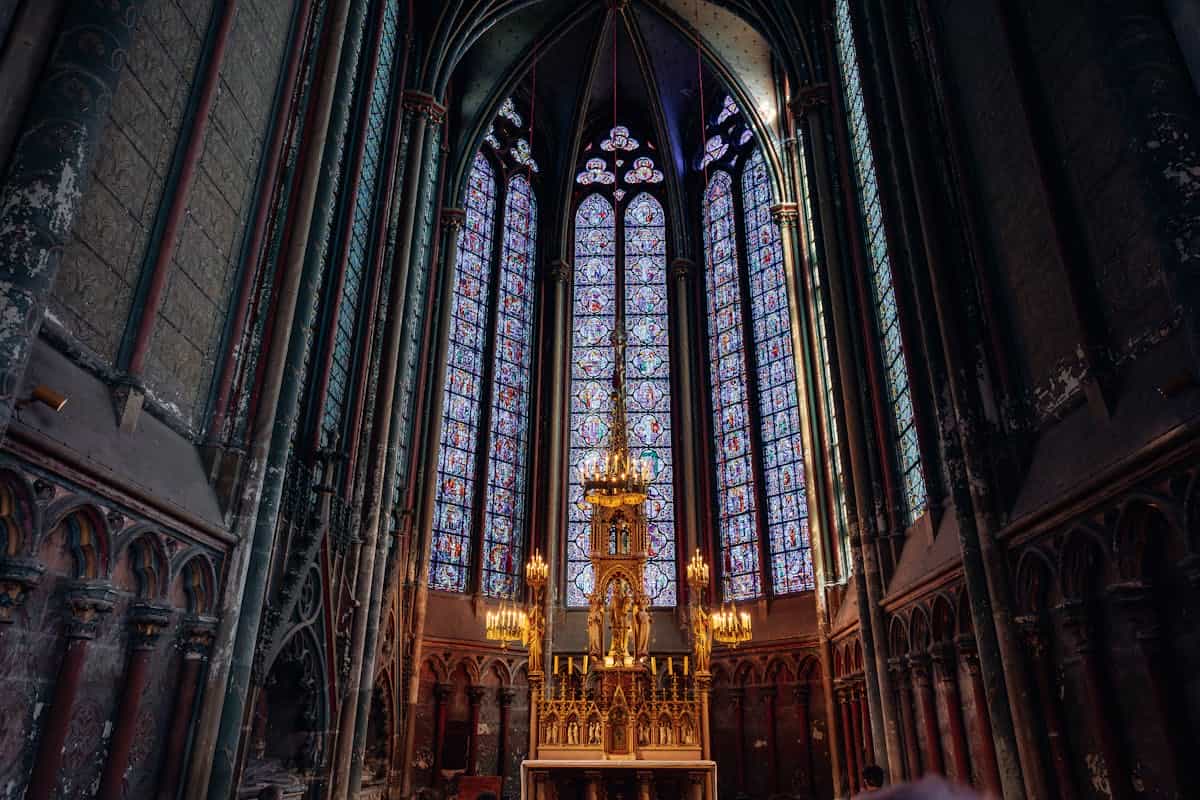 Gothic architecture and stunning stained glass windows in a historic cathedral in Amiens representing the transforming vision of God glory described in 2 Corinthians 3:18